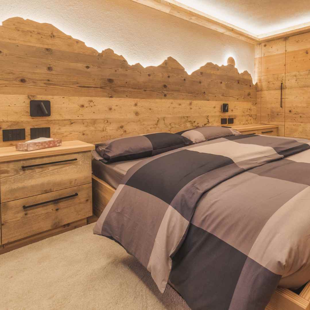 Camera matrimoniale con parete rivestita in legno con profilo di montagna