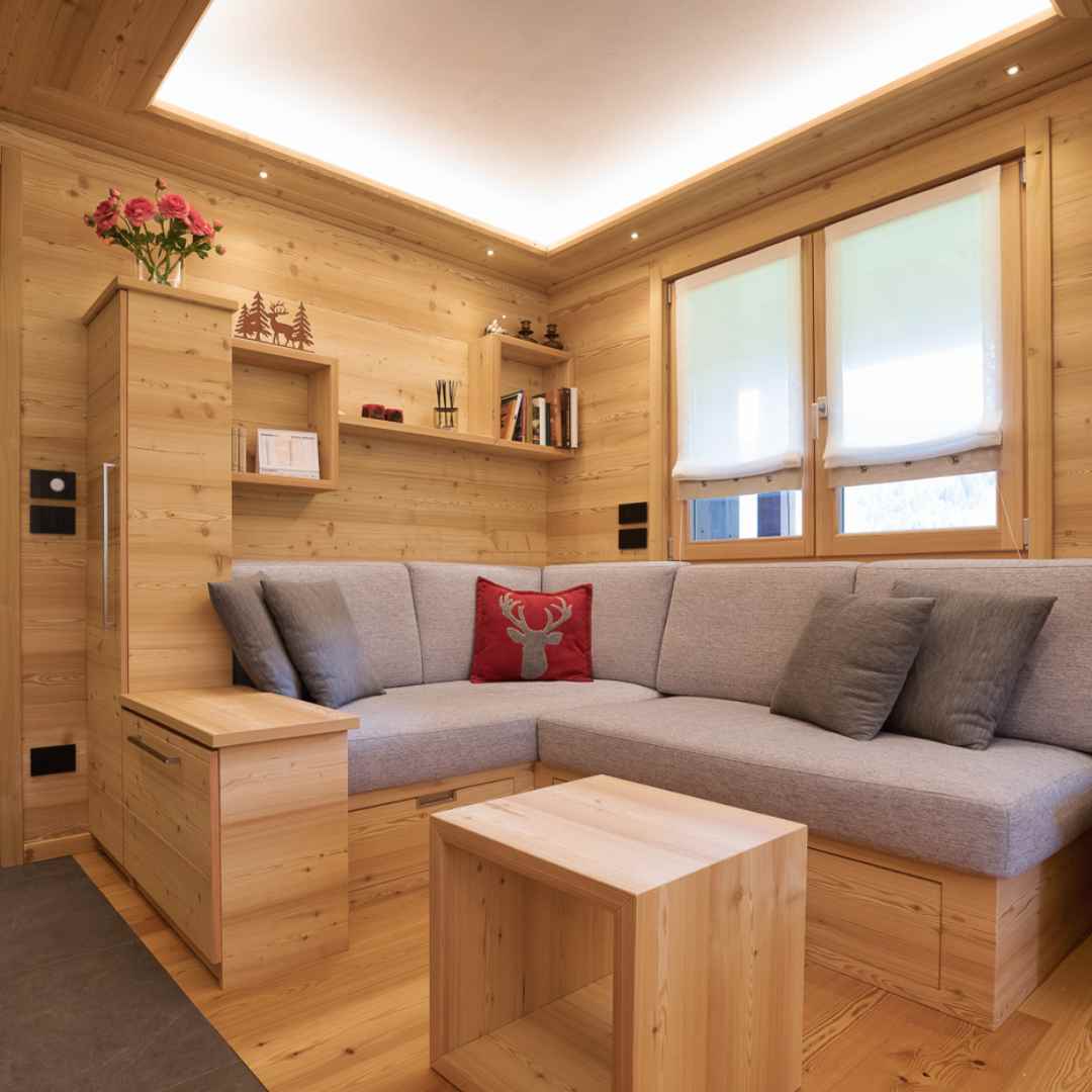Soggiorno in legno di larice con cassettiere e scaffalature su misura