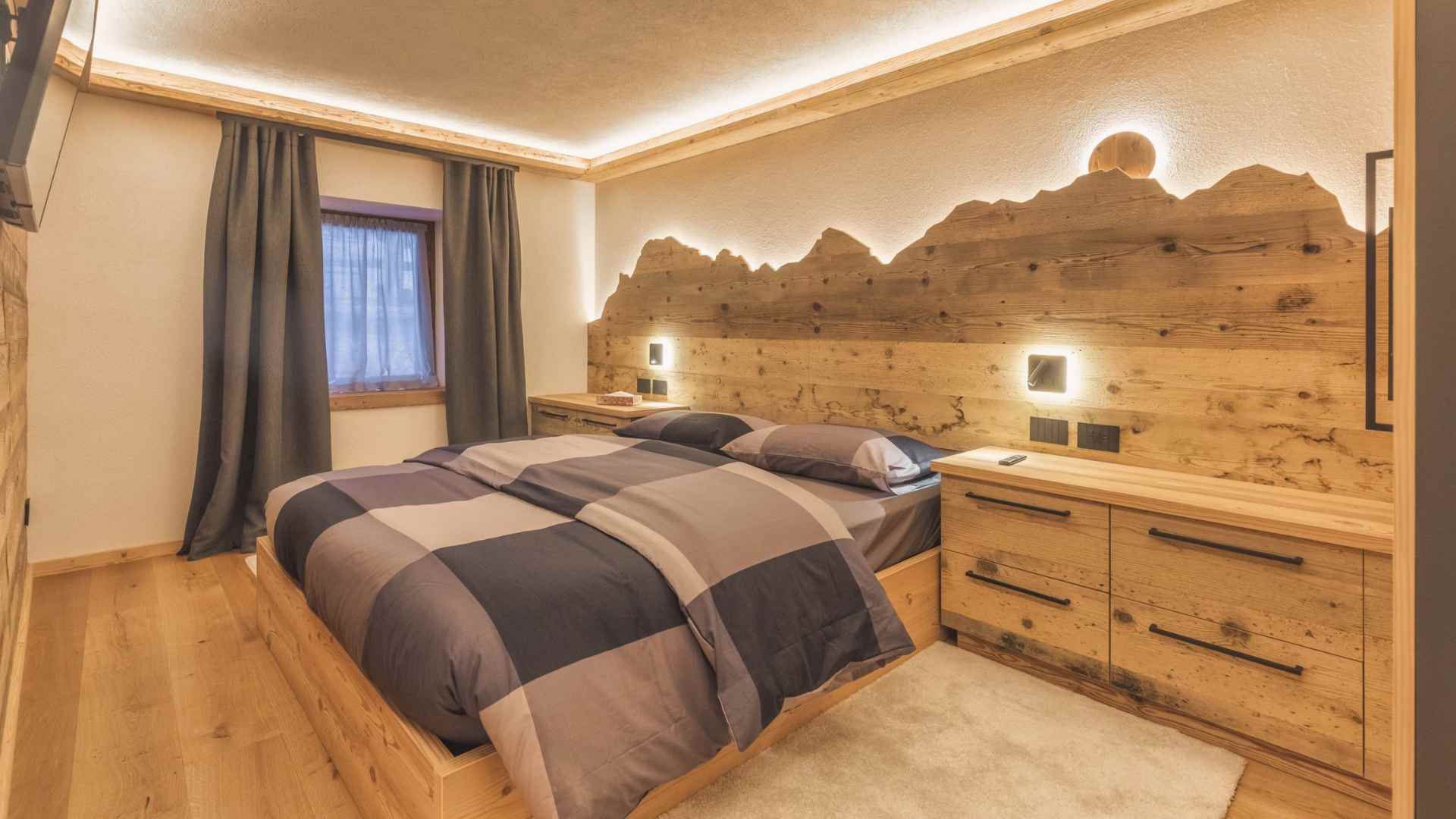 Camera da letto rustica e moderna con testiera retroilluminata a profilo di montagna