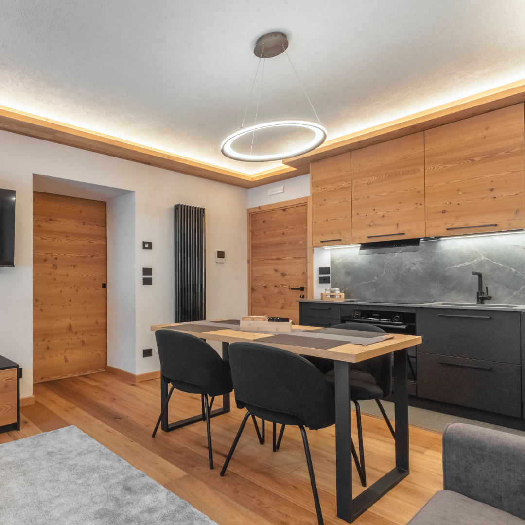 Zona giorno con cucina e tavolo da pranzo in legno e LED perimetrale