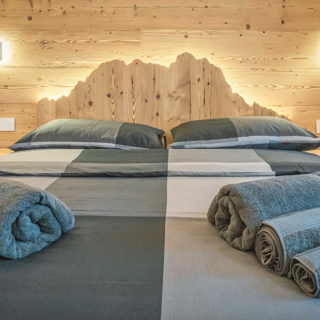 Letto in legno con testiera che rappresenta i profili delle montagne.