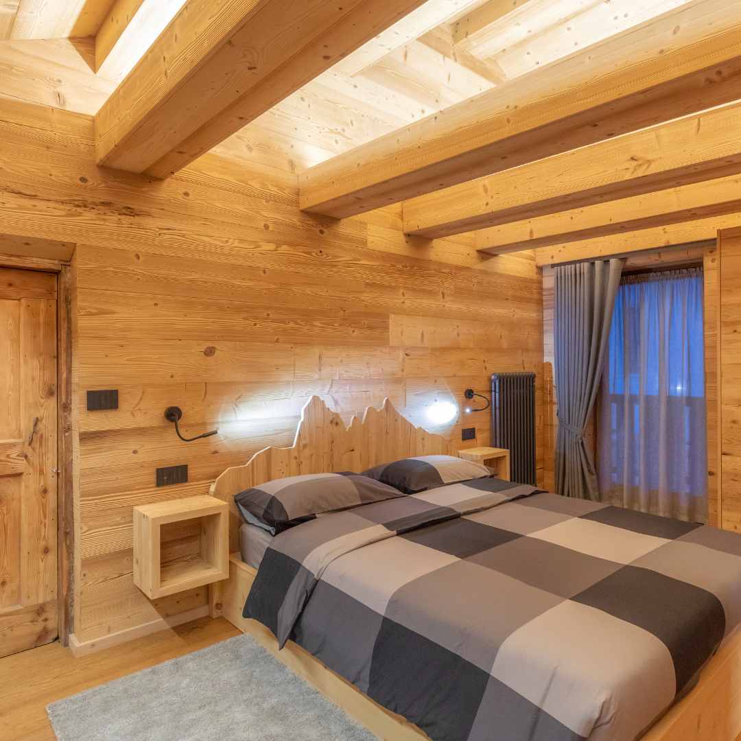 Camera di montagna in legno con travi e testiera letto retroilluminate